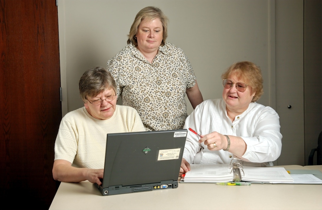 A caregiver and an elderly person looking at a health monitoring app together on a tablet.